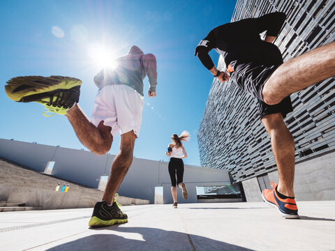 three friends athletes jogging in a modern building district