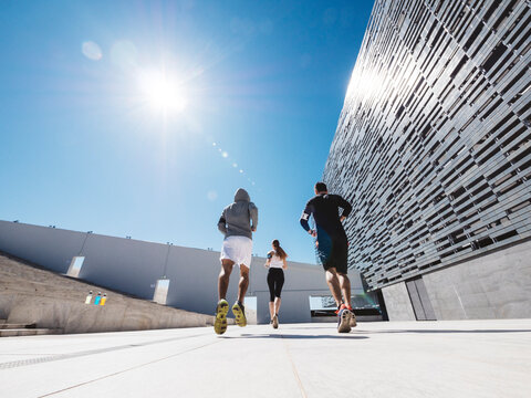 three friends athletes jogging in a modern building district