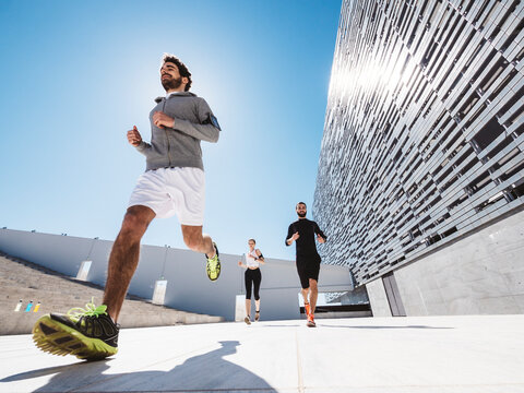 three friends athletes jogging in a modern building district