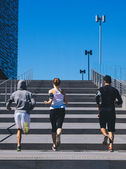 three friends athletes jogging in a modern building district - 401635021