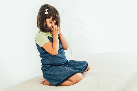 Cute little girl praying at home