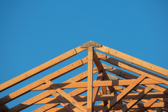 Close-up of the roof Gables on a stick built house under construction and blue sky. New roof design with wooden truss, post and beam frame. Wooden frame house, real estate. 