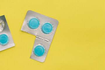 Round pills on a yellow background with copy space. Medicines in silver packaging. Tablets for the treatment of diseases. Pharmaceuticals and Medicine