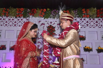 Bride and groom putting garland as a ceremonial proceeding as per Hindu Marriage Rituals and posing...