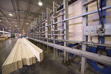 Profiled glued beams are lying near the press. Woodworking production.