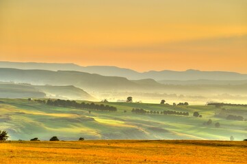 Fototapeta premium DRAKENSBERG FOOTHILLS IN THE DAWN. Summer sunrise over farmlands, district Underberg, Kwazulu Natal, South Africa