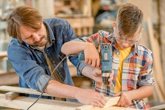 Father teaches young boy carpentry at a workshop