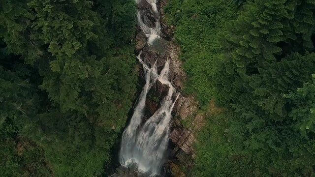 vertical video about a mountain river that turns into a waterfall falling off a cliff in Rosa Khutor National Park