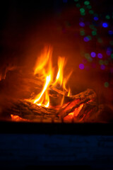 burning fire in the fireplace through the fire glass with reflective lanterns, vertical format