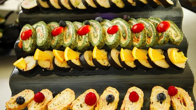 Amlet rolls with spinach and salmon. A dish of Japanese cuisine. Sushi rolls with chuka salad, salmon. Delicious recipe for omelet. Sushi roll with shrimps, avocado, cheese, omelet. 