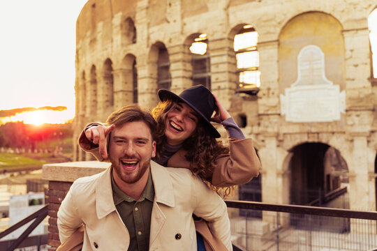Happy couple of travelers having fun, girl pointing forward. Happy tourists visiting famous monuments. Honeymoon trip, tourism, love vacation and vacation trip concept.