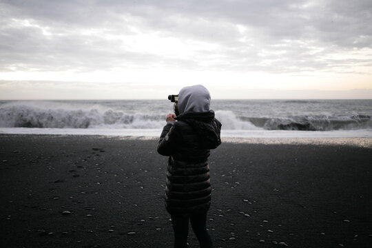 A woman taking photos in icelandic black sand beach