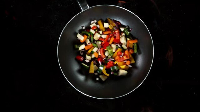 Super slow motion of flying sliced vegetable pieces from wok pan with fire. Filmed on high speed cinema camera, 1000 fps.