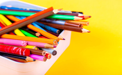Lots of different colorful wooden crayons, many multi colored crayons mixed in a box container, closeup. Back to school, art class drawing supplies early education simple abstract background