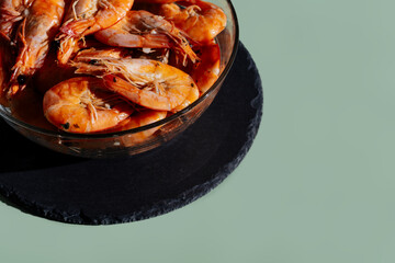 Shrimps in a transparent bowl on an olive background.  King prawns on an olive-gray background.
