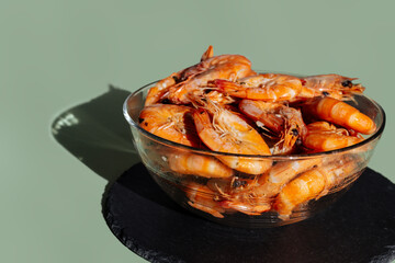 Shrimps in a transparent bowl on an olive background.  King prawns on an olive-gray background.