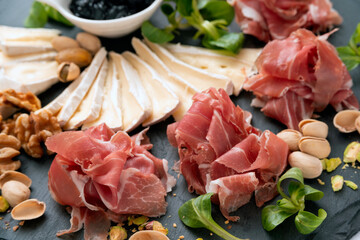 Tagliere con prosciutto crudo, brie, confettura di frutta, pistacchi e noci, antipasto italiano