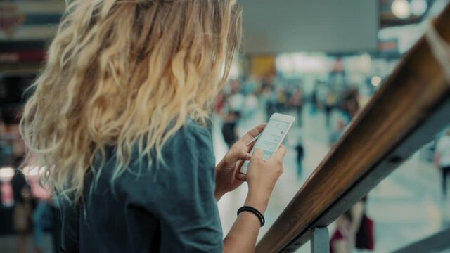 Young woman text chat with friends on social media platform in busy street market, train station platform or airport terminal. Stay connected when travelling, international data coverage network