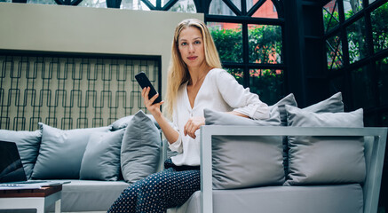 Obraz premium Serious female employee using smartphone in cafe