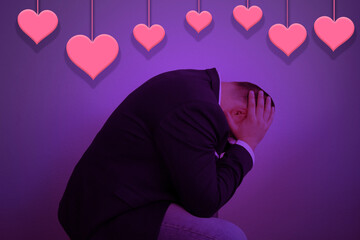 hearts hanging on the background, a businessman sitting, clasped his head in his hands, purple background, concept forgot to buy a gift for Valentine's Day