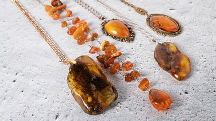 Different sparkling old Baltic amber pendants and amber necklace on the gray plastered background....