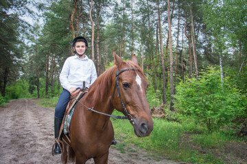 On a sunny summer day in the forest, a boy riding a horse.