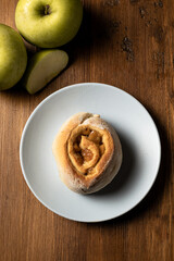 Vegan cinnamon roll made with apple on a wooden board.
