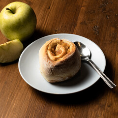 Vegan cinnamon roll made with apple on a wooden board.
