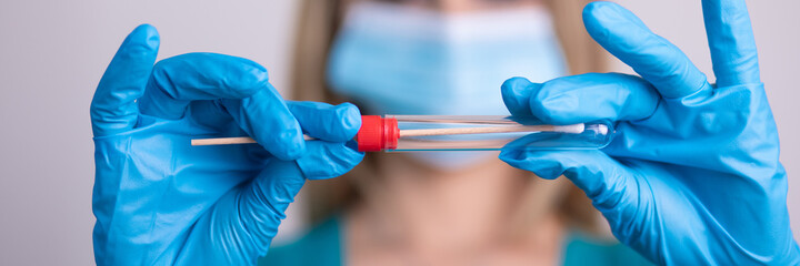 Nurse with facemask holding Coronavirus COVID-19 swab test kit, PPE protective mask and gloves, tube for taking OP NP patient specimen sample, PCR DNA RNA testing protocol process