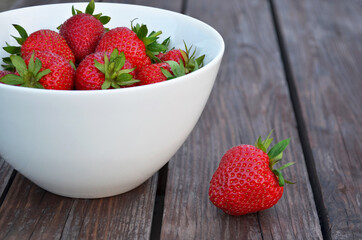 Bowl of ripe strawberries on a old wooden table close-up. Healthy eating concept.