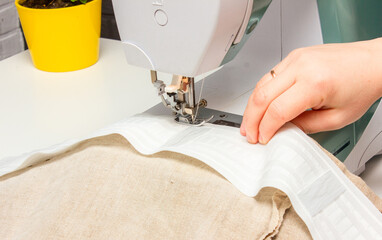 The woman is doing housework, sewing curtains. freelance. sewing curtains