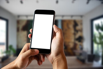 Hand holding white mobile phone with blank white screen in cafe.