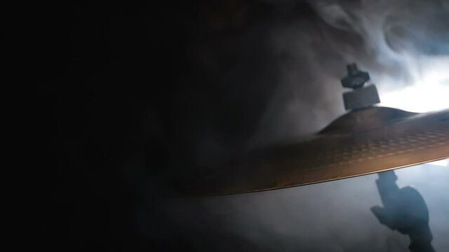 Close-up of a musical cymbal on a drum kit on black background. The drum stick hits it with force . Slow motion 200 fps