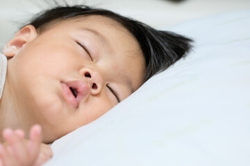 An asian baby boy sleeping on white bed