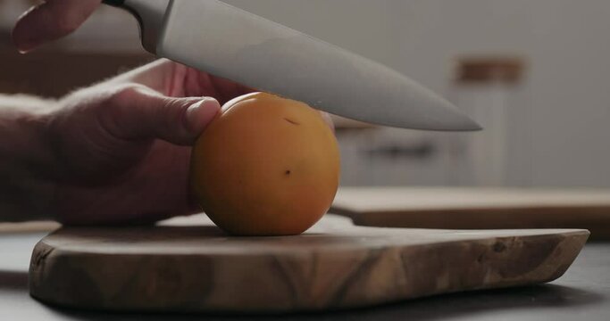 Slow motion man cut lulo fruit on olive wood board with copy space