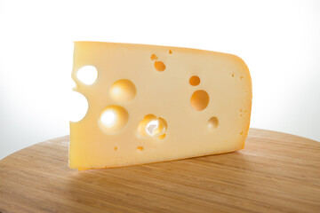 Yellow cow's milk Swiss cheese emmenthal with holes on wooden board..