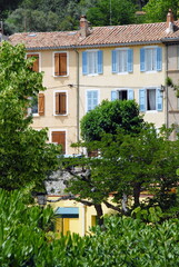 Fototapeta na wymiar Ville de Gémenos, jolie façade colorée en centre ville, arbres en premier plan, département des Bouches-du-Rhône, France