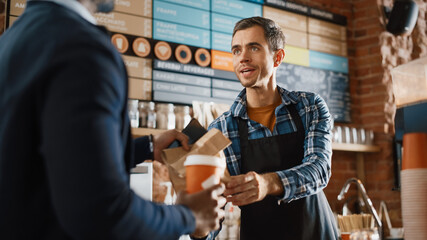Handsome Barista in Blue Checkered Shirt Passes Coffe and Paper Bag with Pastry to an African American Customer. Concept of Buying Food and Drink in Modern Stylish Cafe.