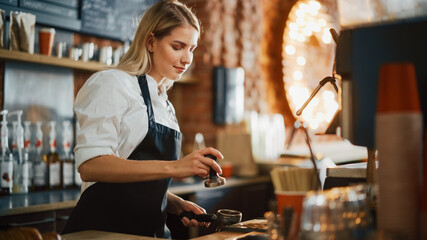 Beautiful Young Caucasian Barista with Blond Hair is Making a Cup of Fresh Coffee in a Cafe. Happy and Smiling Bar Employee Posing while Working in a Cozy Loft-Style Coffee Shop Restaurant Counter.