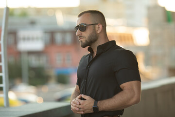 Sexy stylish man in sunglasses. City style. A beautiful and charming man with sunglasses outdoors.