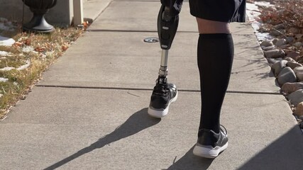 Black man artificial prosthetic leg walks down sidewalk up stairs