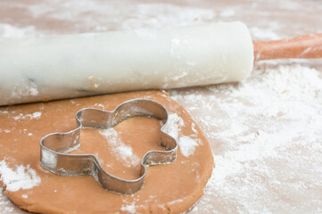 The process of baking cookies at home, closeup on cookie cutter on dough and rolling pin
