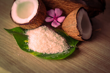 Cracked coconut and grated coconut flakes on wooden,coconut and coconut milk in glass on wooden table, fresh and healthy coconut milk and half coconut fruit,selective focus on subject,