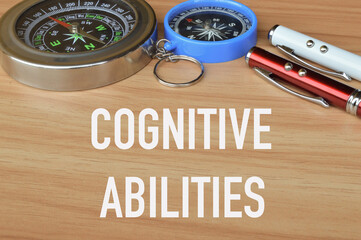 Selective focus of compasses and pens over wooden background written with text COGNITIVE ABILITIES.
