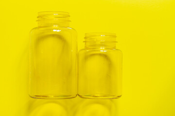 Two transparent plastic empty cans on a yellow background. Copy space.