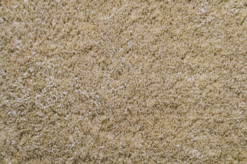 Texture of beige frieze carpet. Artificial wool material carpeting.