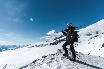 A man with skis stands high in the mountains enjoying the scenery. Go downhill skiing, extreme...