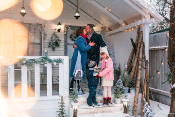 Fototapeta na wymiar Happy family on the porch of the Christmas decorated house outdoor