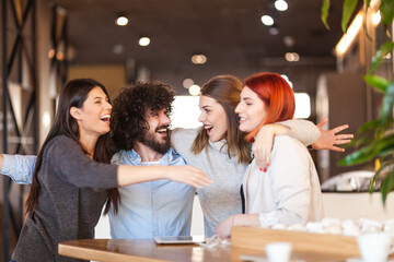 Four friends at a cafe having fun and cheering. Successful young people