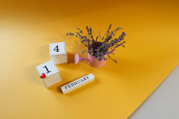 Calendar for February 14: lavender bouquet in a pink watering can, red heart, numbers one and four, name of the month in English, yellow-gray background, top view